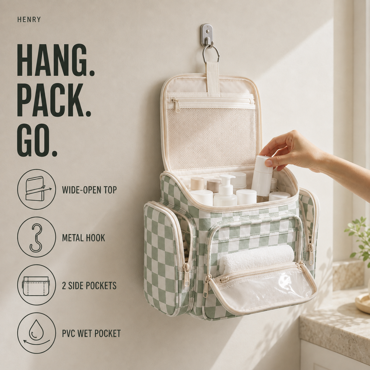 Sage-green hanging toiletry organizer open in a bathroom with mesh pockets, elastic bottle loops, side pockets, a metal hook and carry handle